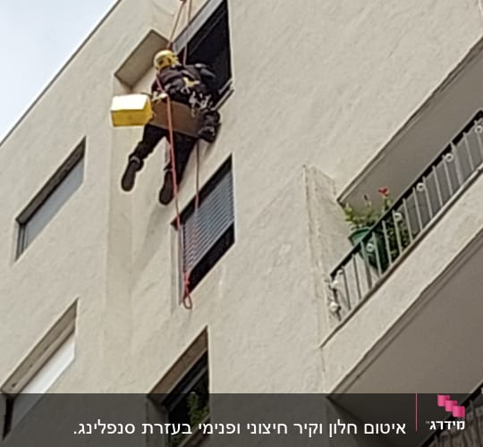אדם תלוי על חבל ליד חלון בניין